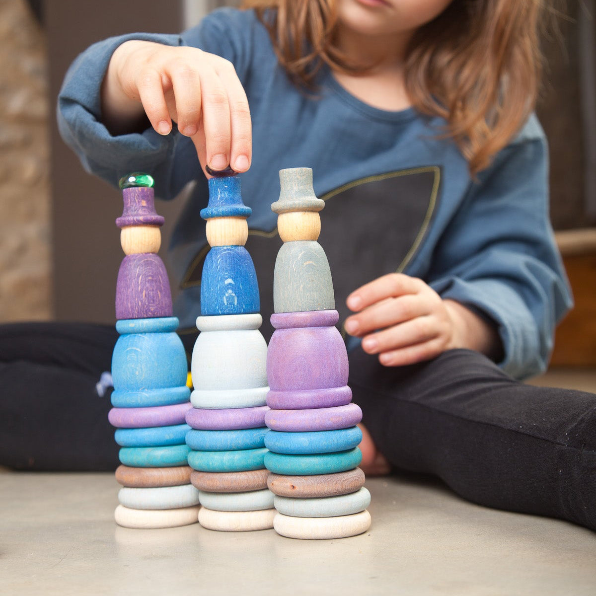 Child stacking colorful wooden rings on a table