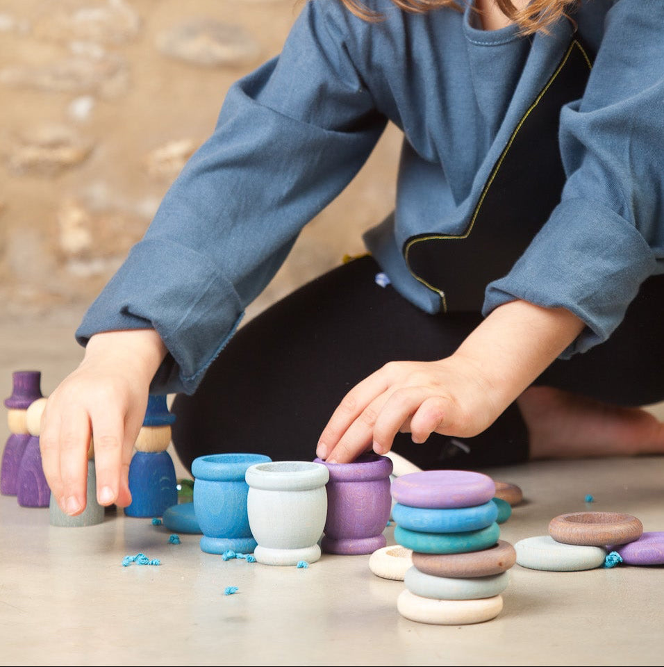 Child playing with colorful stacking toys on a stone floor.