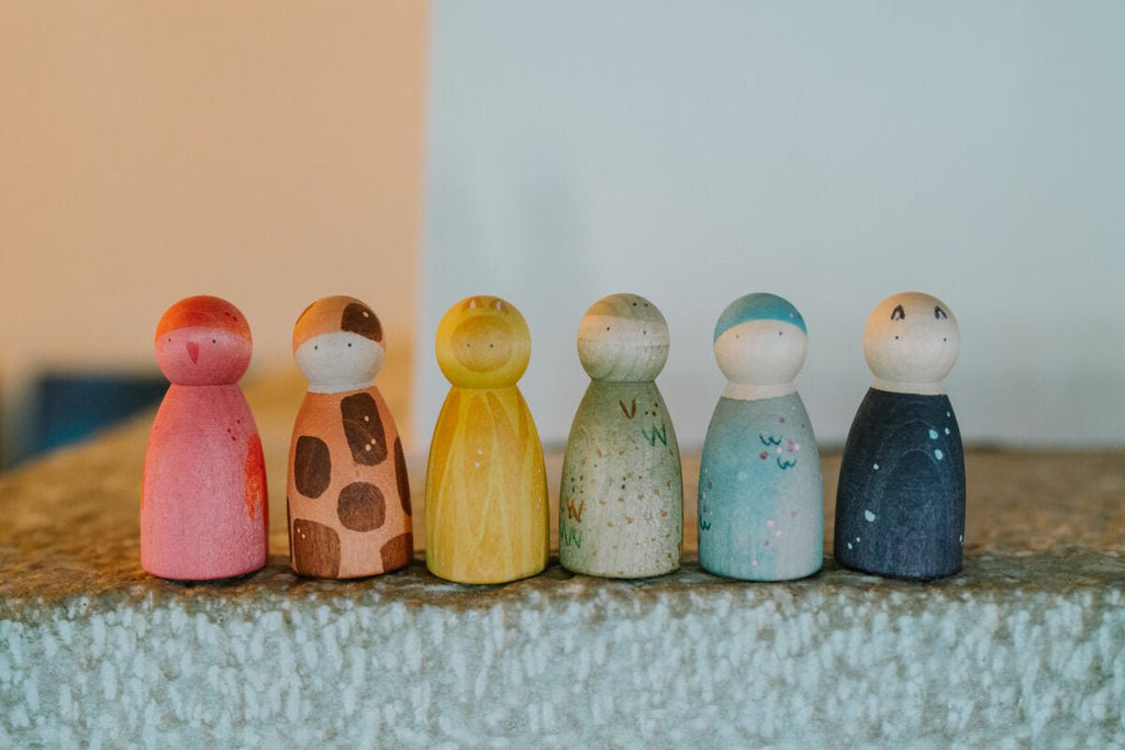 Set of colorful wooden peg dolls on a textured surface with a neutral background