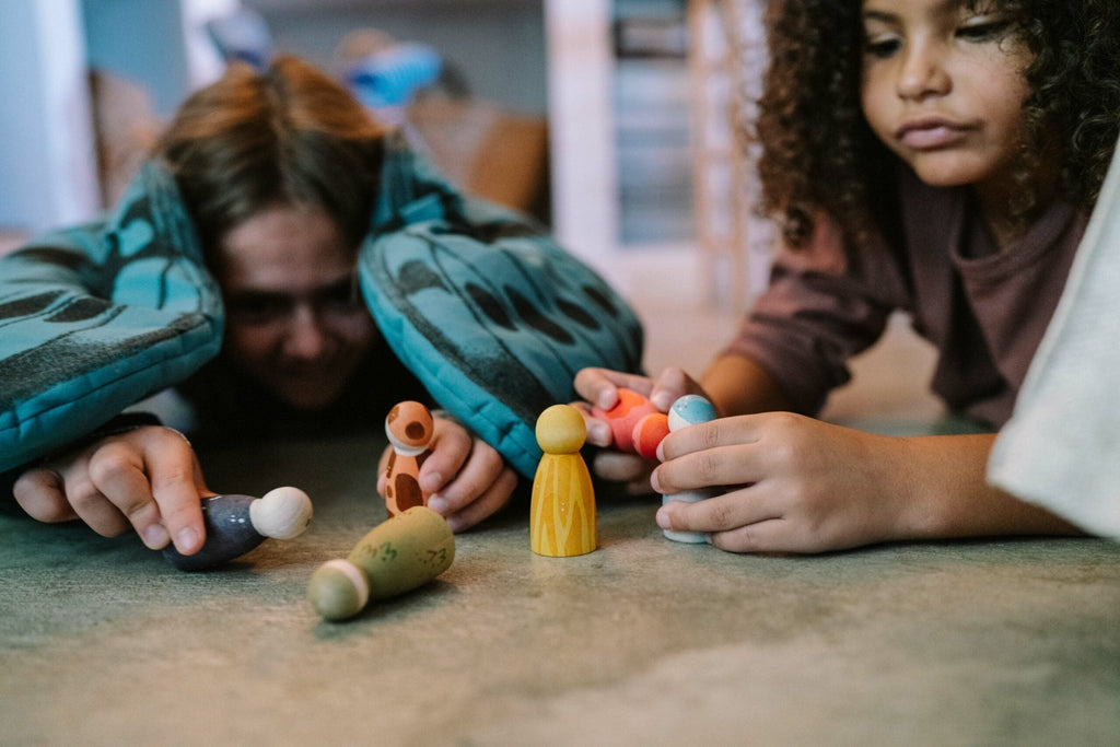 Two children playing with colorful toys on a carpeted floor.