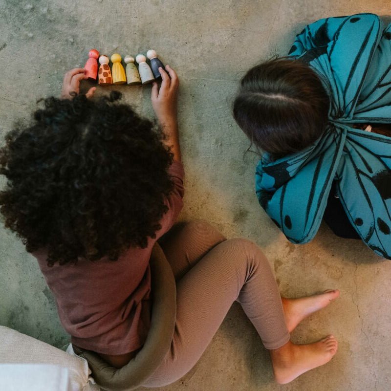 Two children playing on a concrete floor with colorful toys.