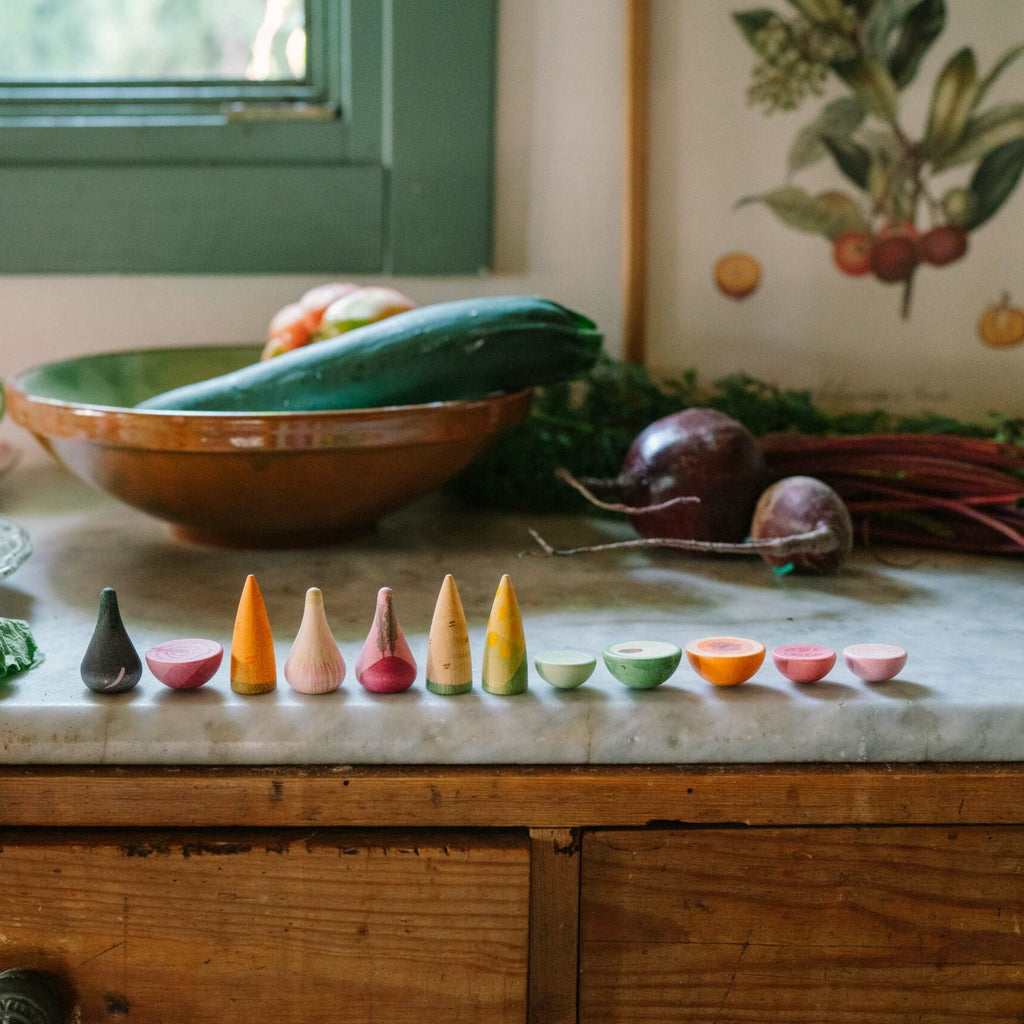 Kitchen counter with vegetables and a row of small colorful pots on a wooden cabinet.