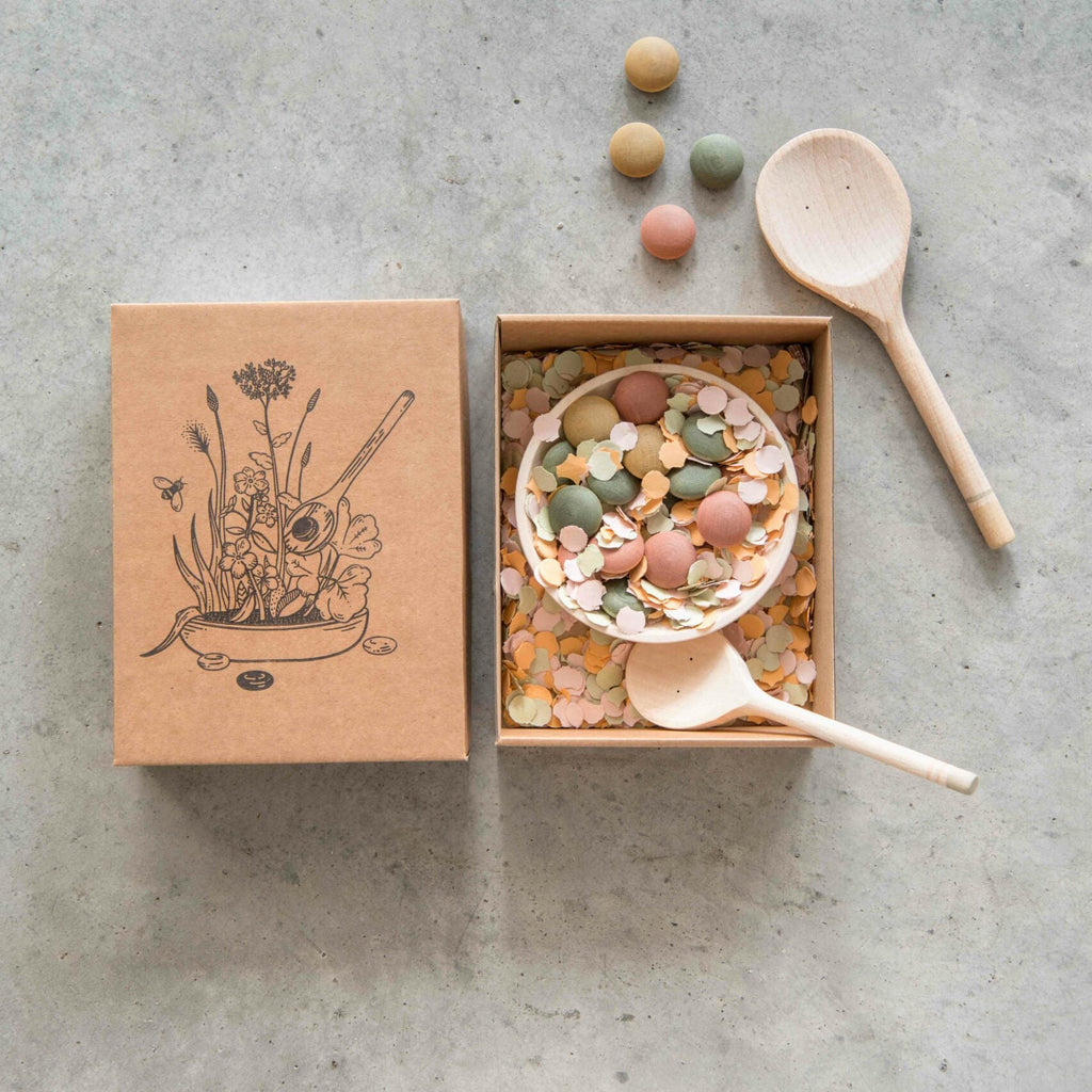 Wooden box with decorative lid, contents, and wooden spoons on a concrete surface