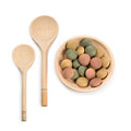 Three wooden spoons and a bowl with colorful stones on a white background