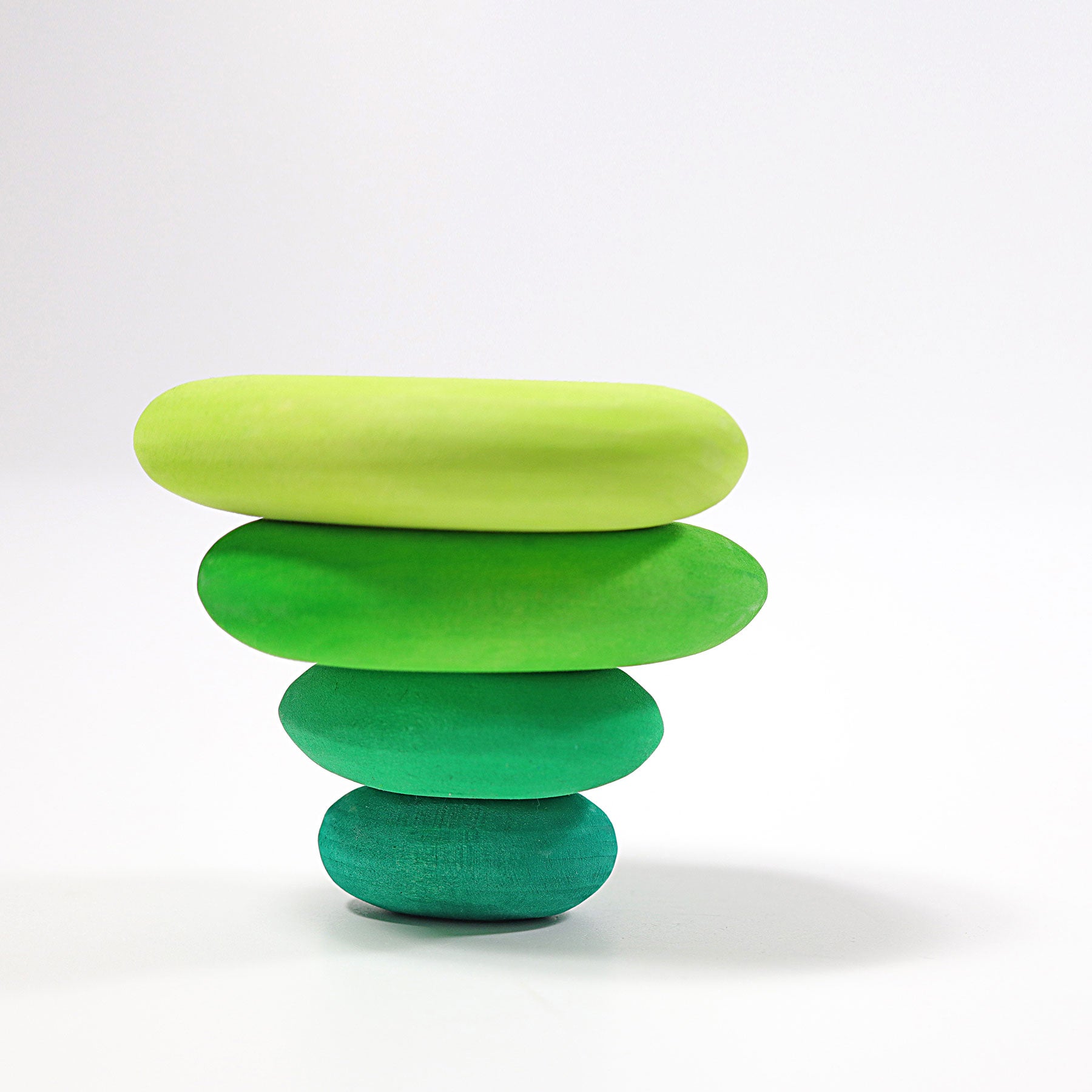 Stack of four green wooden stones on a white background
