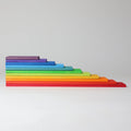 A set of rainbow-colored wooden blocks stacked in a stepped, pyramid-like arrangement on a light gray background.
