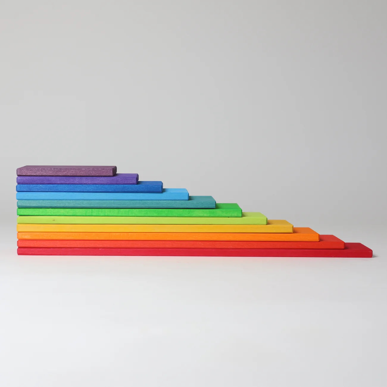 A set of rainbow-colored wooden blocks stacked in a stepped, pyramid-like arrangement on a light gray background.