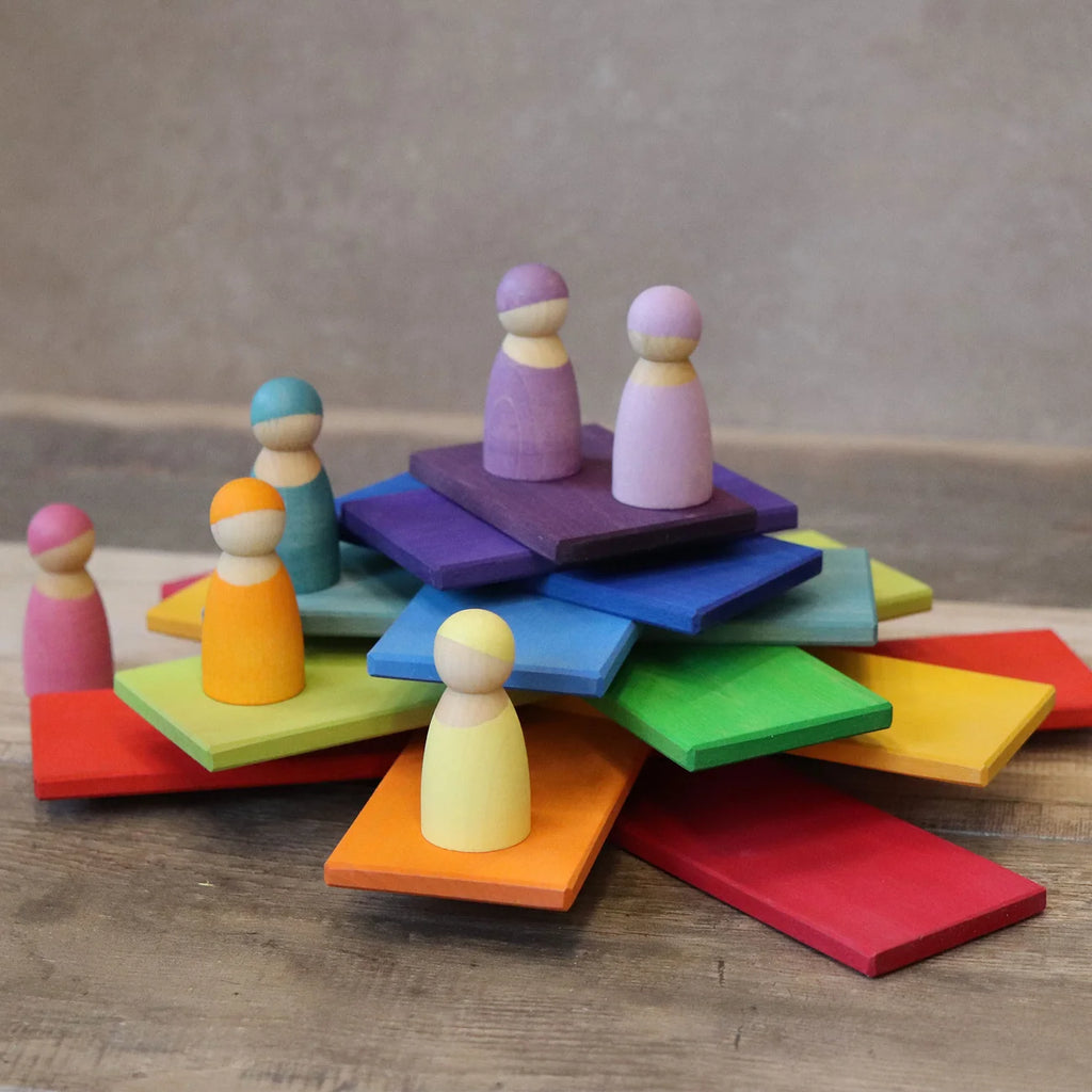 Colorful wooden peg people on a wooden surface with a neutral background