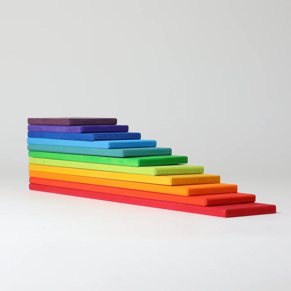 A set of rainbow-colored wooden blocks arranged in a staircase pattern on a light gray background.