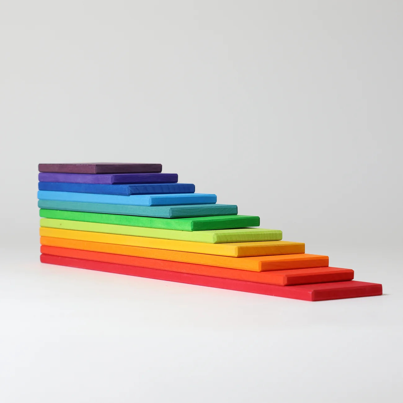 A set of rainbow-colored wooden blocks arranged in a staircase pattern on a light gray background.