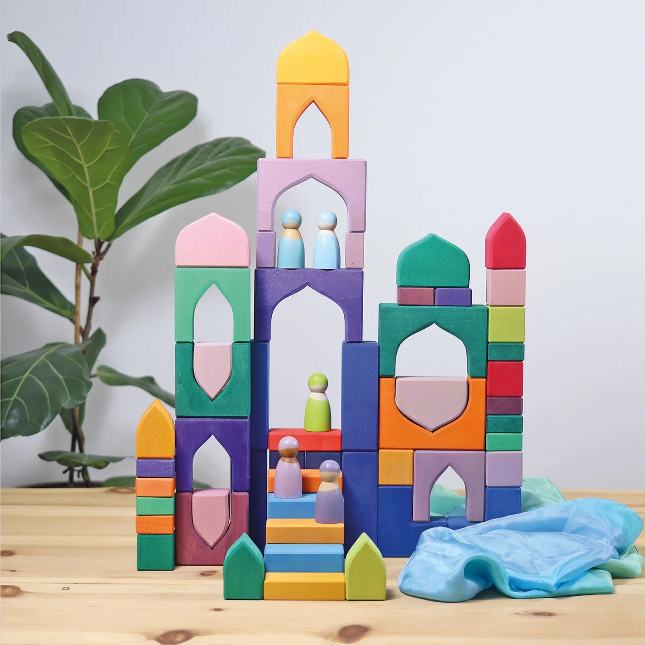 Colorful toy blocks stacked on a wooden surface with a plant in the background