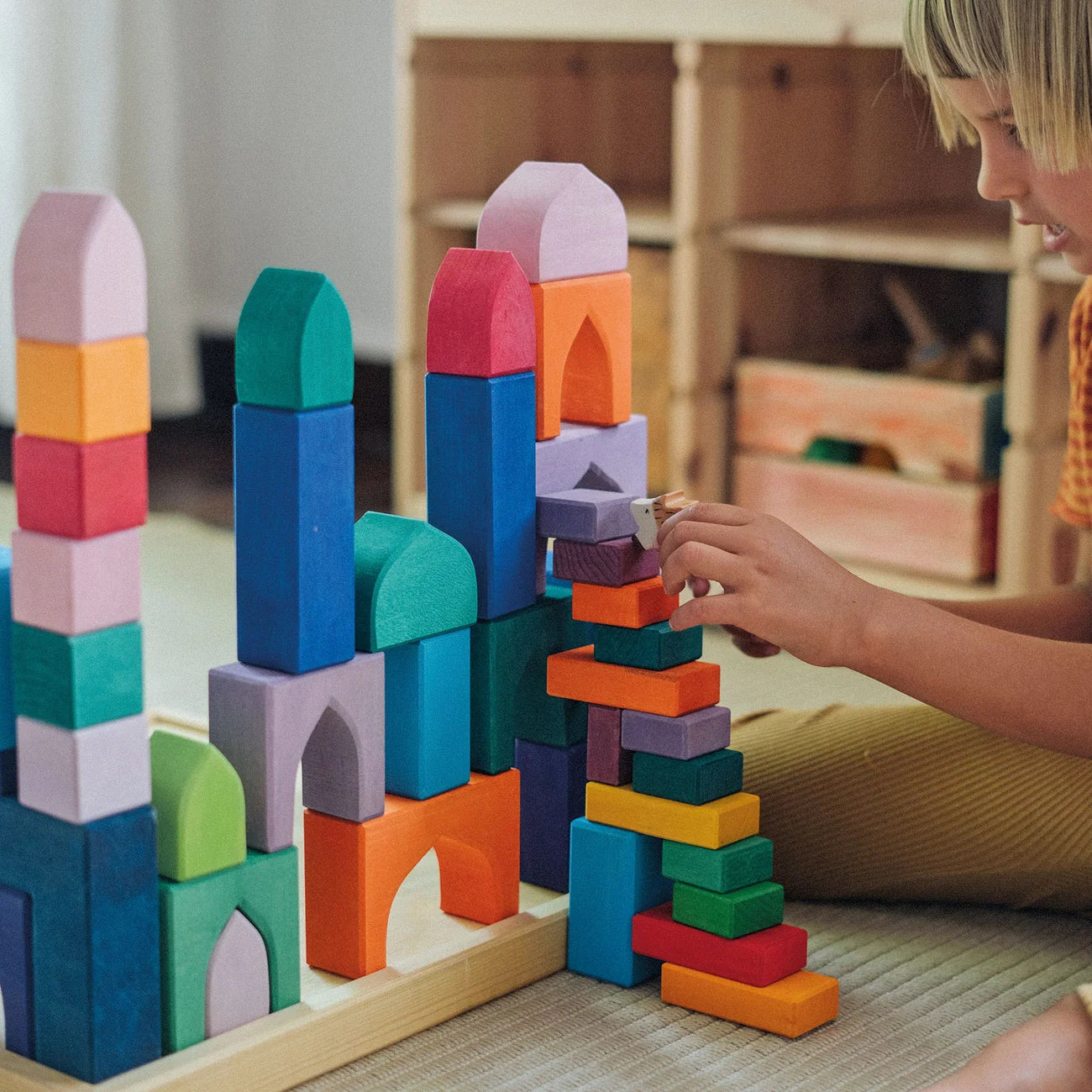 Child playing with colorful wooden building blocks indoors