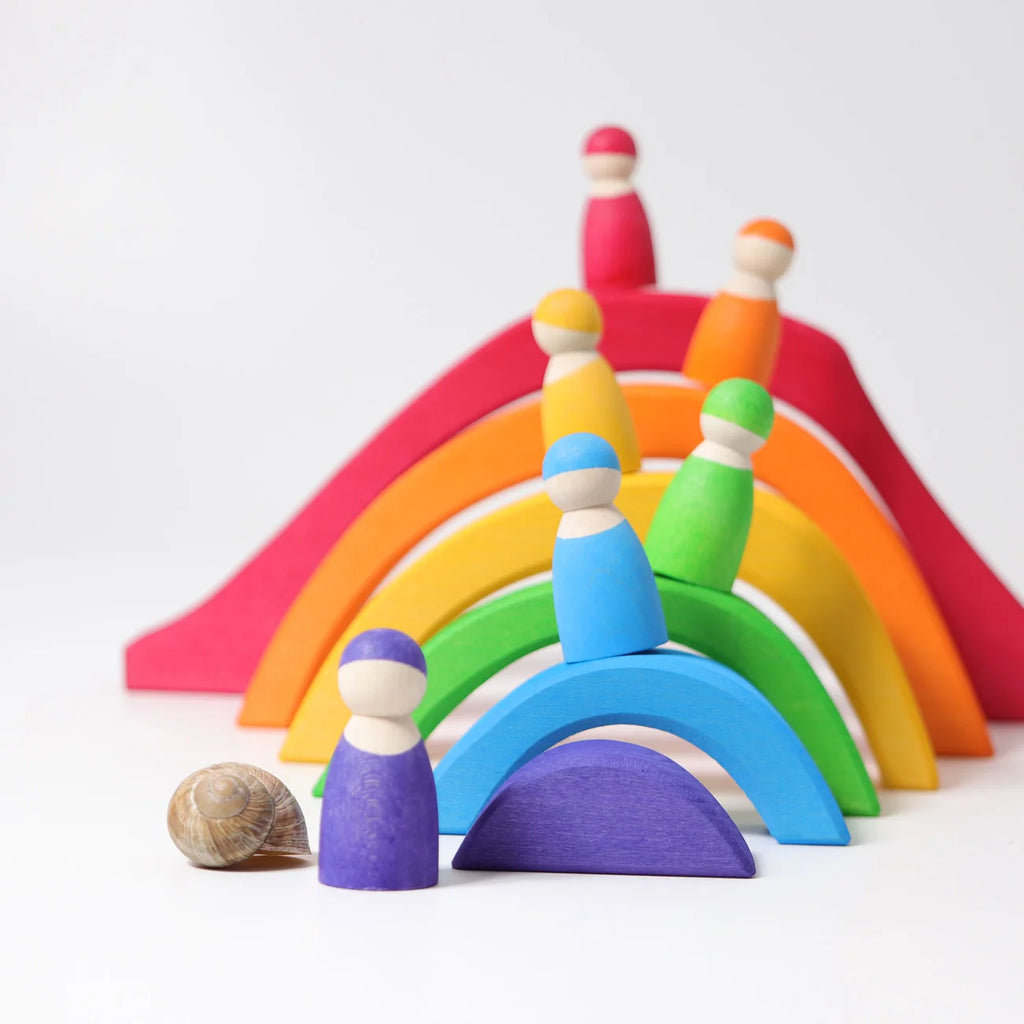 Colorful wooden toy set with rainbow arches and peg people on a white background