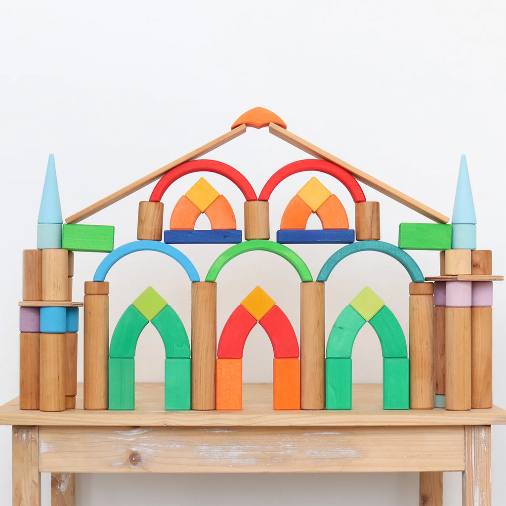 Colorful wooden arch-shaped blocks on a wooden table with a white background