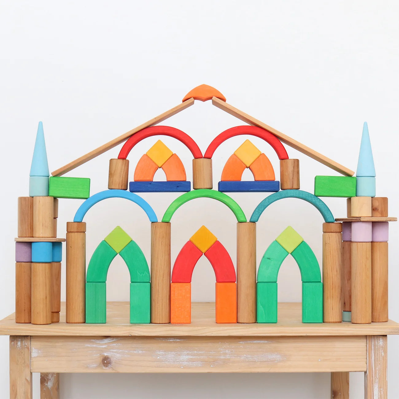 Colorful wooden arch-shaped blocks on a wooden table with a white background