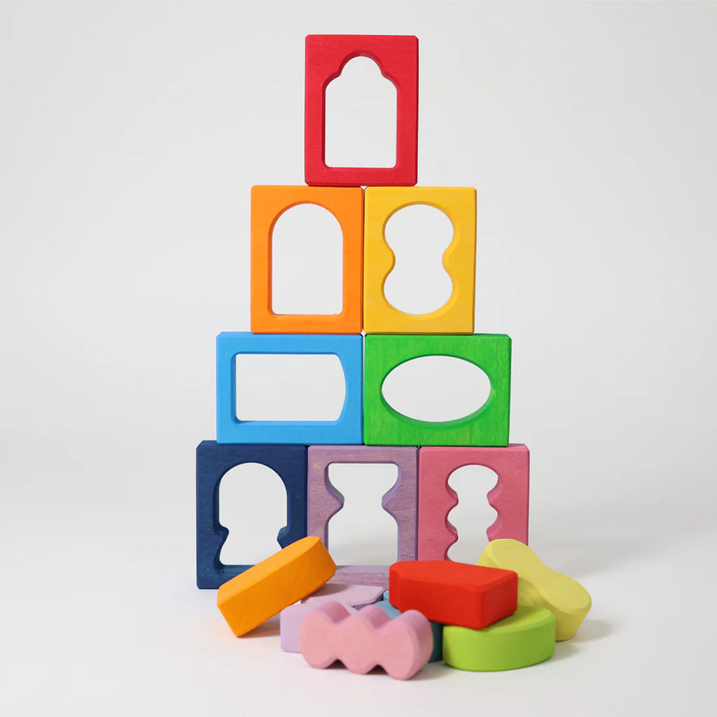 Colorful wooden blocks with cut-out shapes stacked on a white background