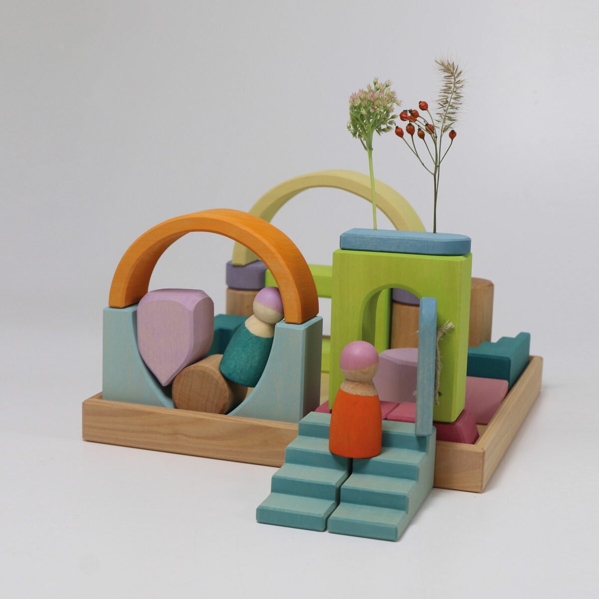 Colorful wooden toy set with arches, steps, and a figure on a light gray background
