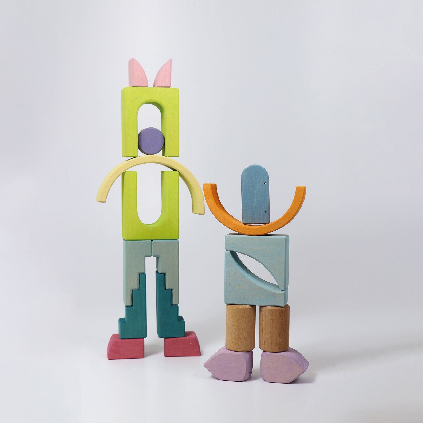 Colorful wooden block sculptures of two abstract figures on a white background