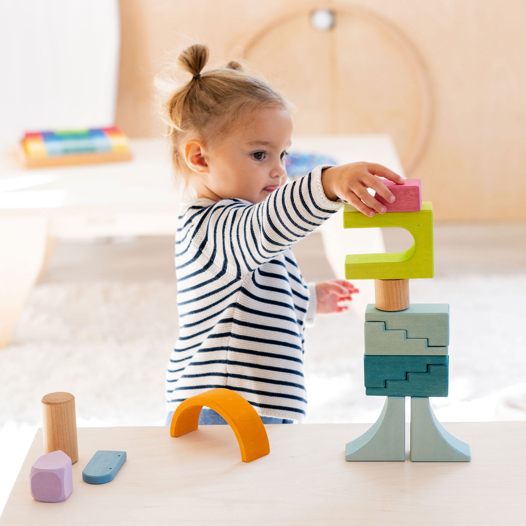 Child playing with colorful wooden blocks on a table