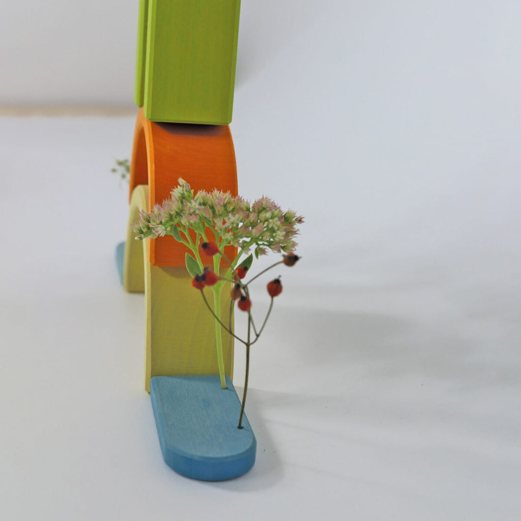 Colorful wooden toy slide with a plant on a white background