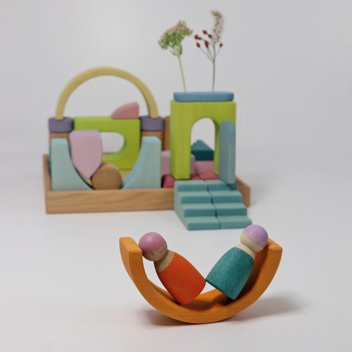 Colorful wooden toy set with a child on a swing against a plain background