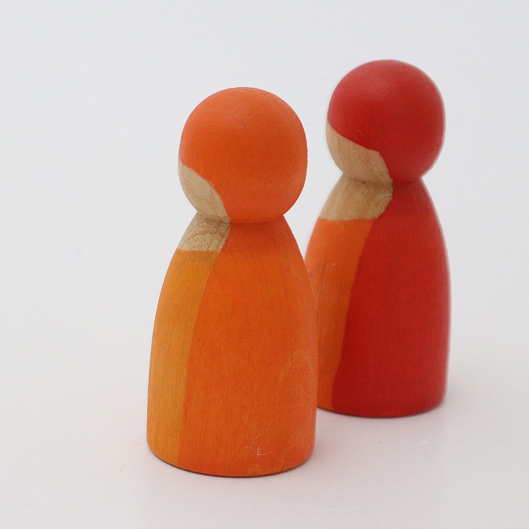 Two wooden peg dolls, one orange and one red, on a white background