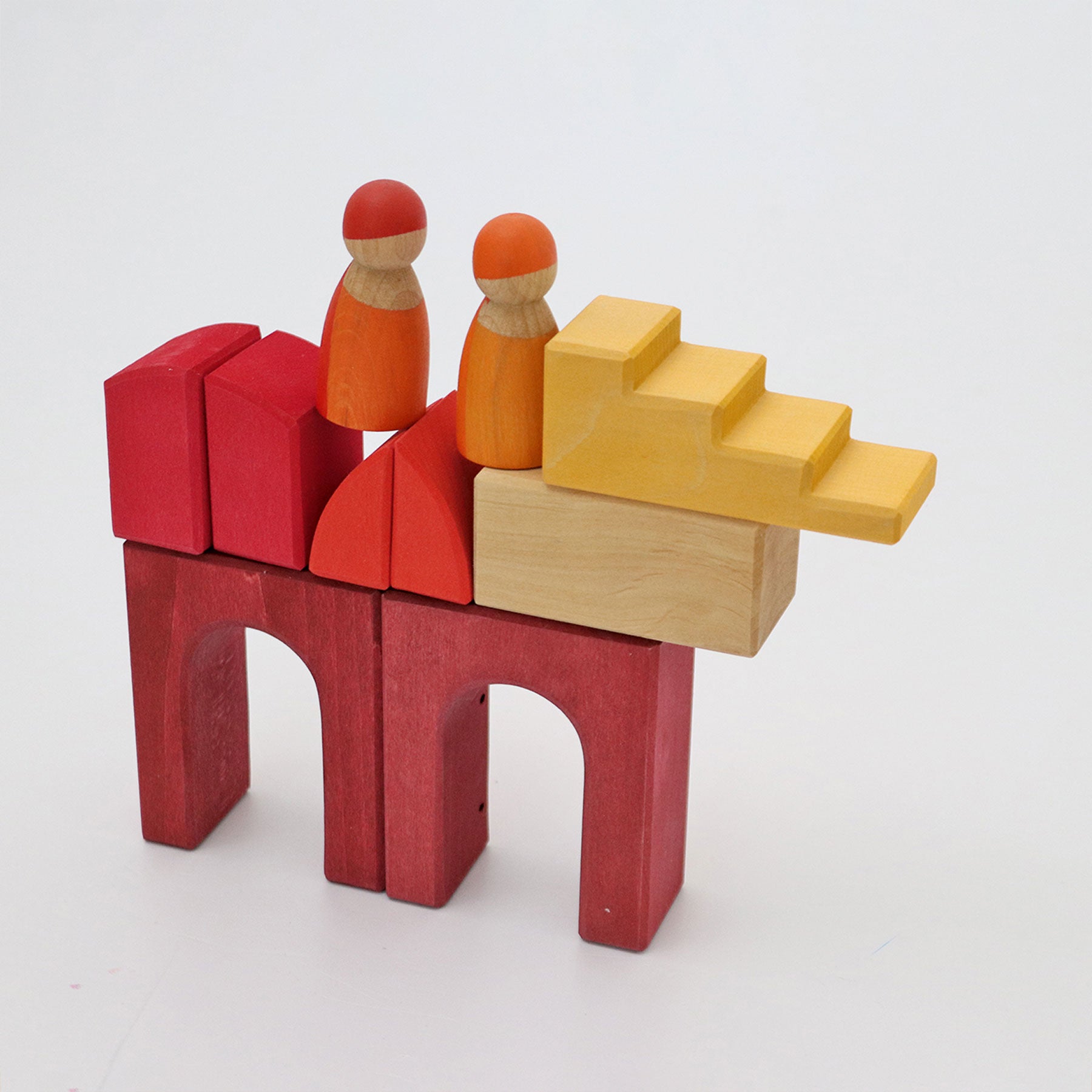 Wooden toy structure with red and yellow blocks and two small figures on a white background
