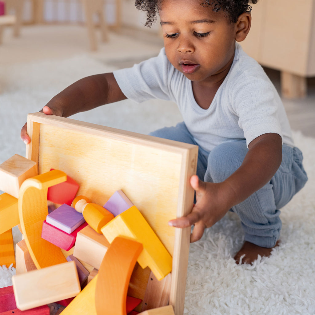 Child playing with wooden blocks on a white carpet