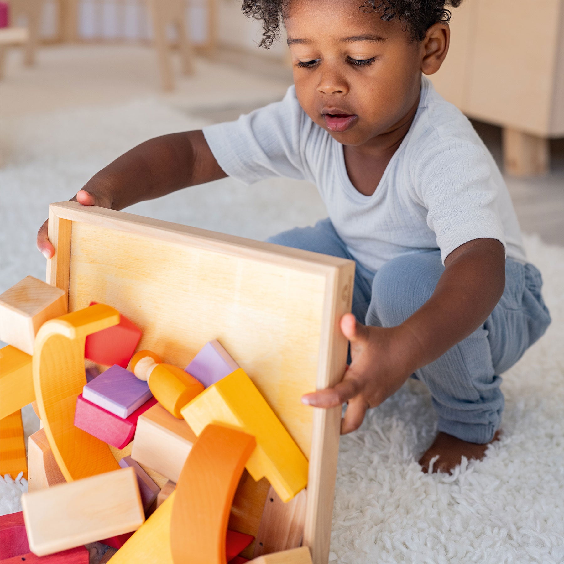 Child playing with wooden blocks on a white carpet