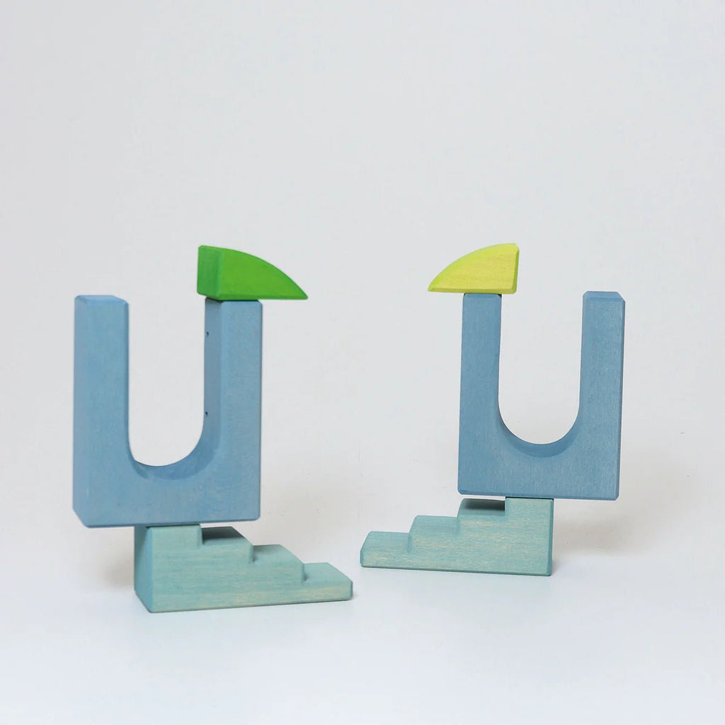 Two blue letter 'U' shaped objects with green tops on a white background