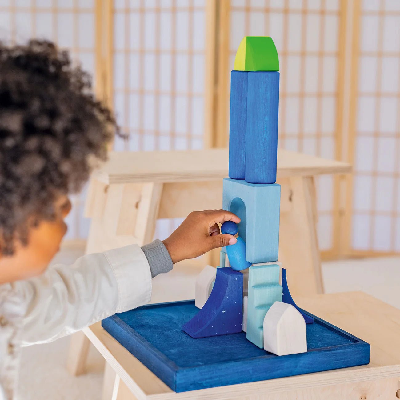 Child playing with a colorful wooden block set on a table.