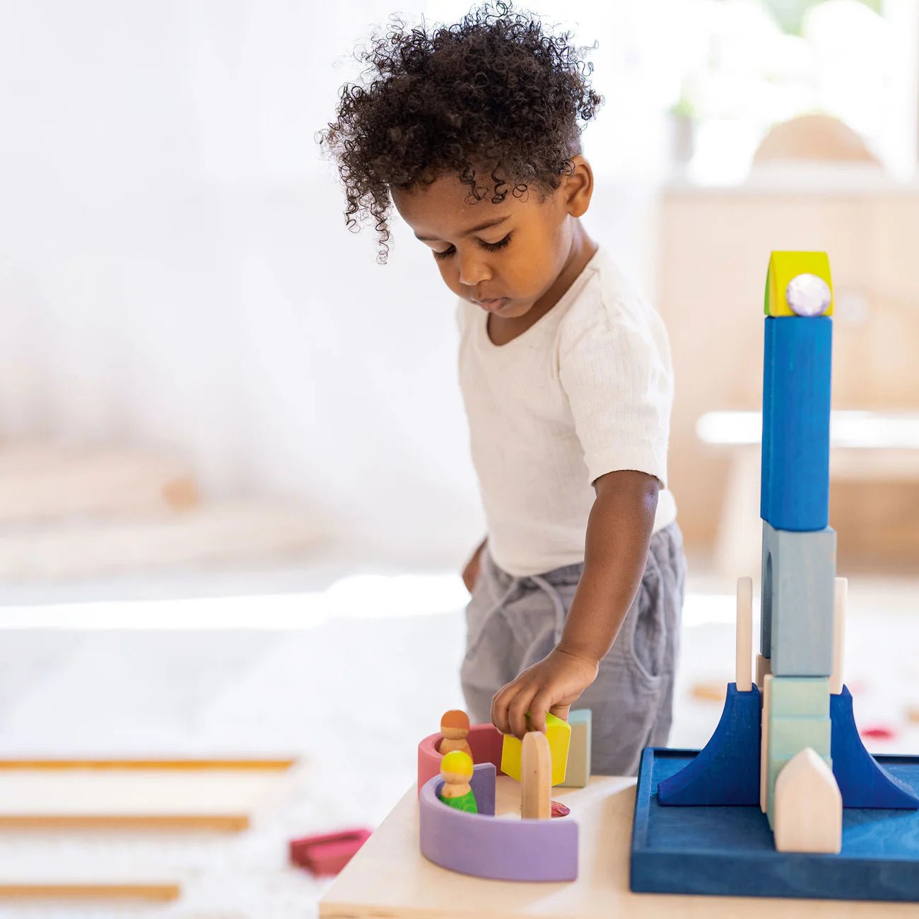 Child playing with a colorful toy set on a table
