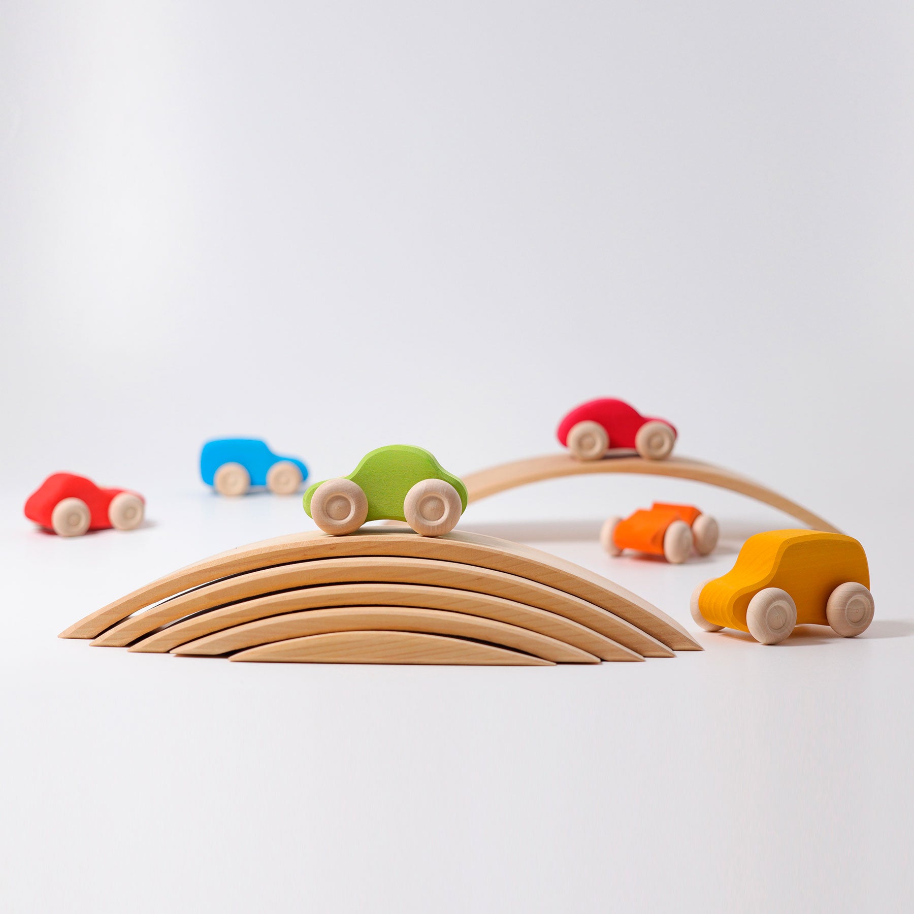 Colorful wooden toy cars on a wooden track against a white background