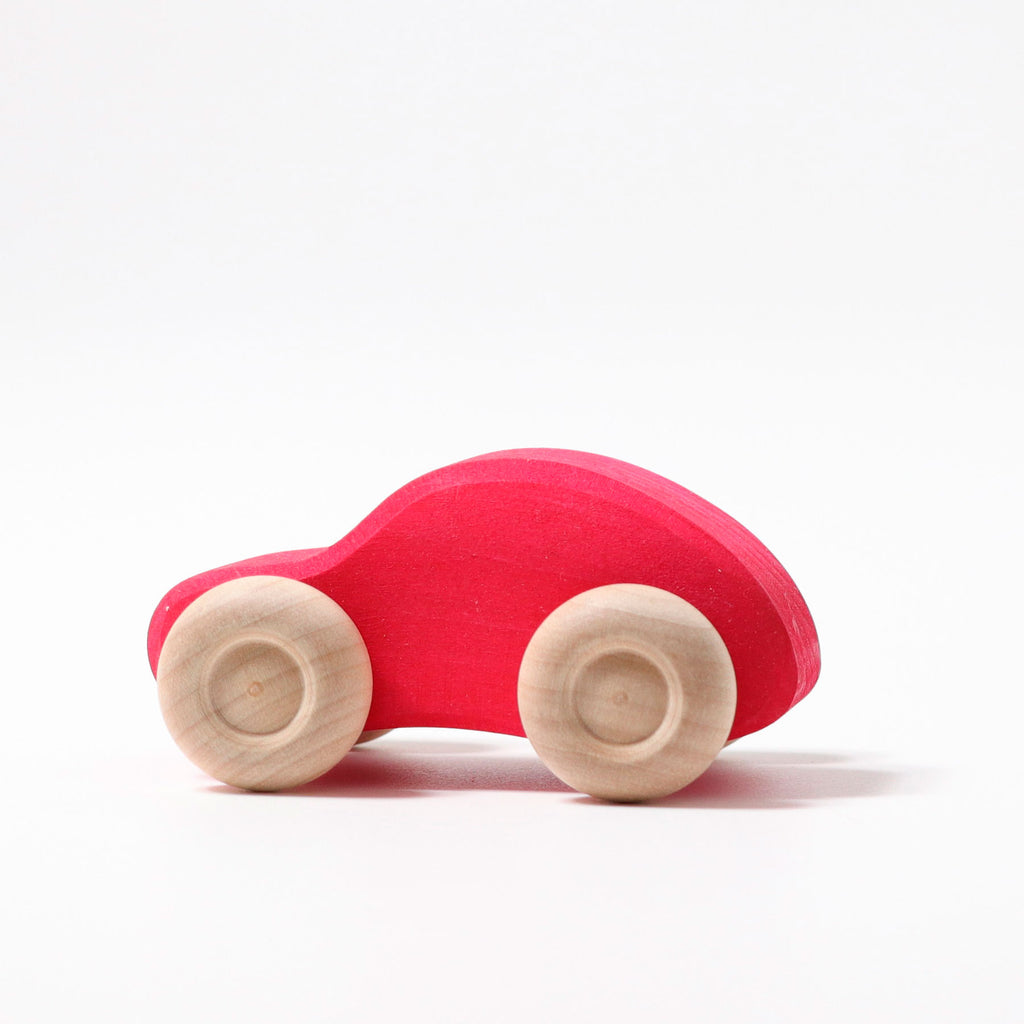 Red wooden toy car with beige wheels on a white background