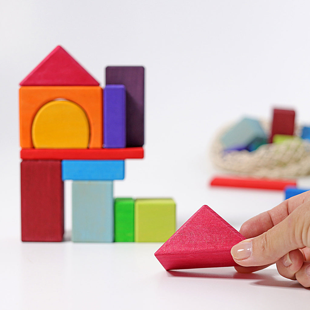 Colorful wooden blocks being arranged by a hand on a light background