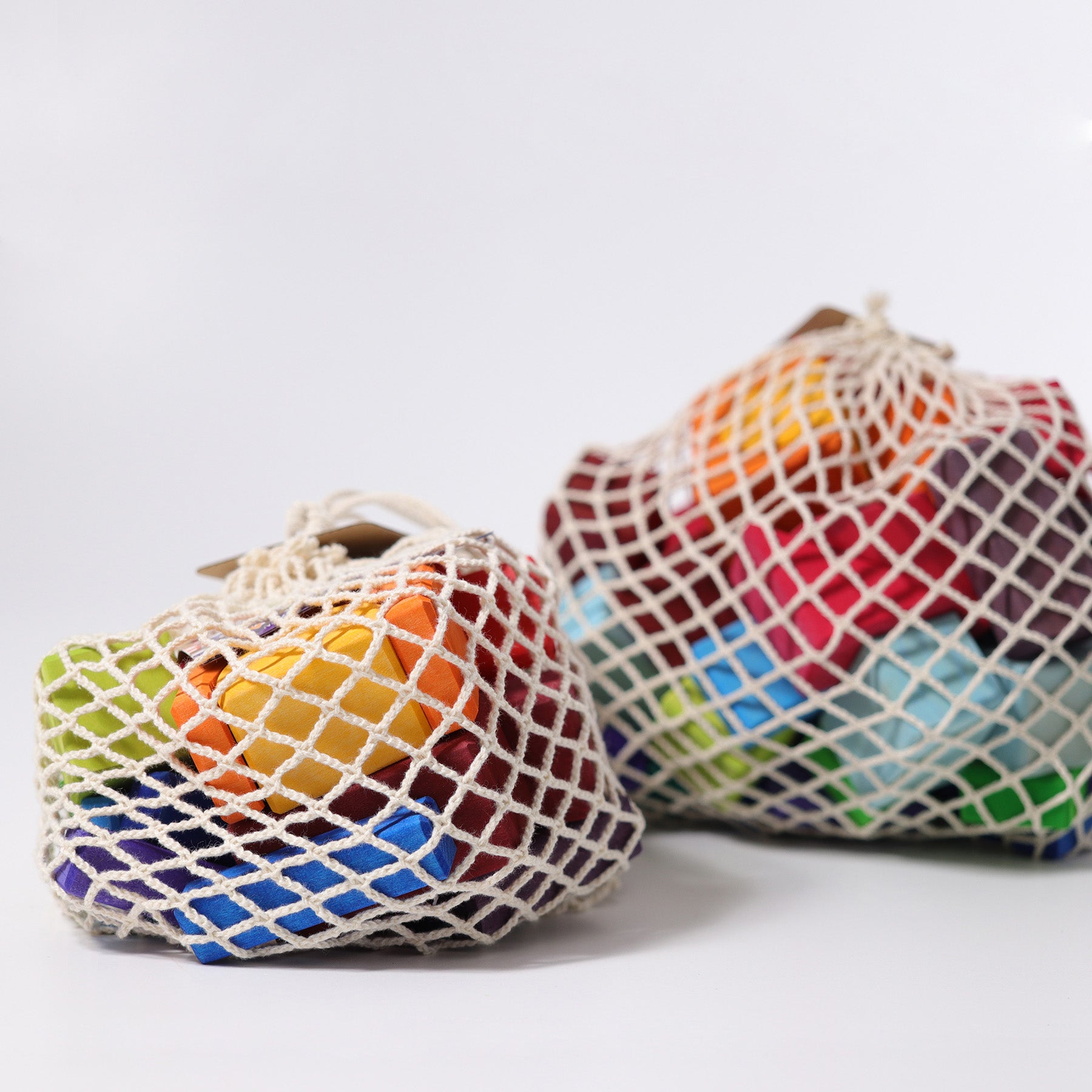 Two colorful mesh bags filled with items on a white background