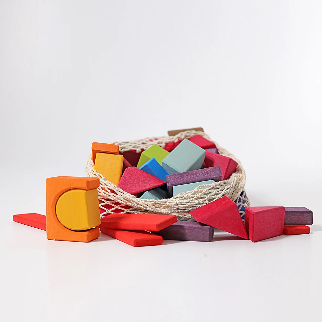 Colorful wooden blocks scattered around a woven basket on a white background
