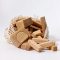 Wooden building blocks scattered on a white surface with a mesh bag.