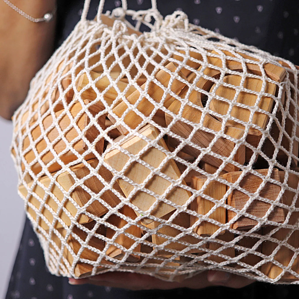 Wooden blocks in a white mesh bag held by a person