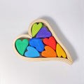 Wooden heart-shaped puzzle with colorful heart pieces on a light gray background