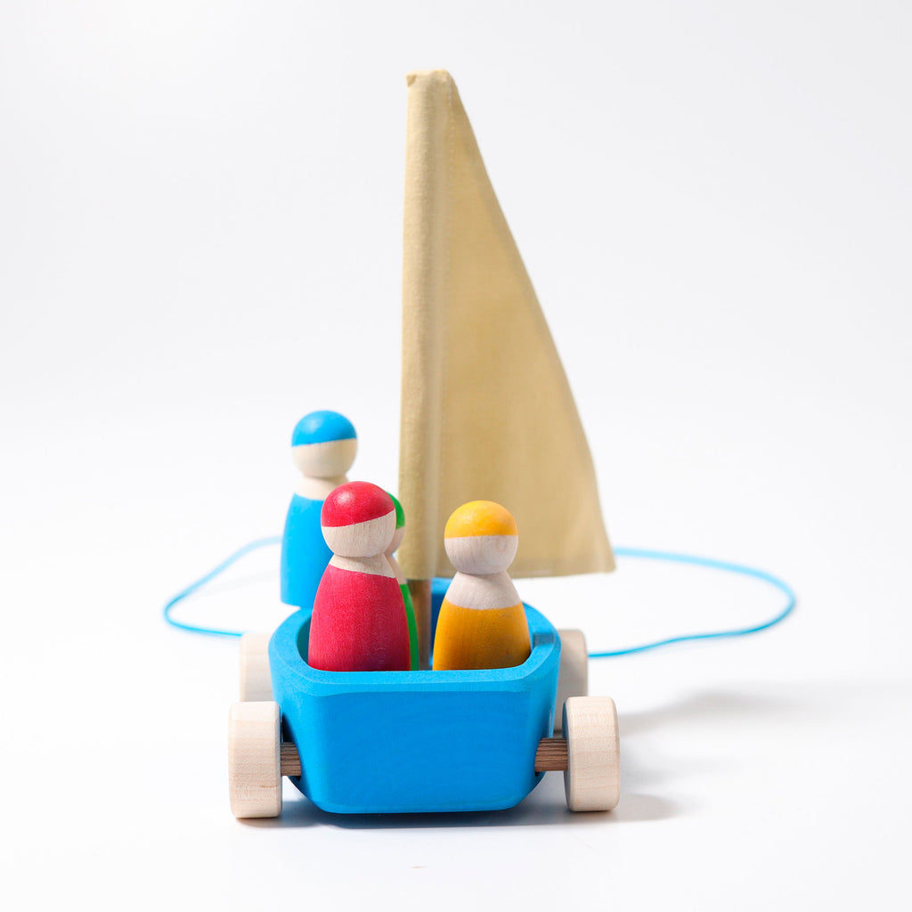 Wooden toy sailboat with colorful figures on a white background
