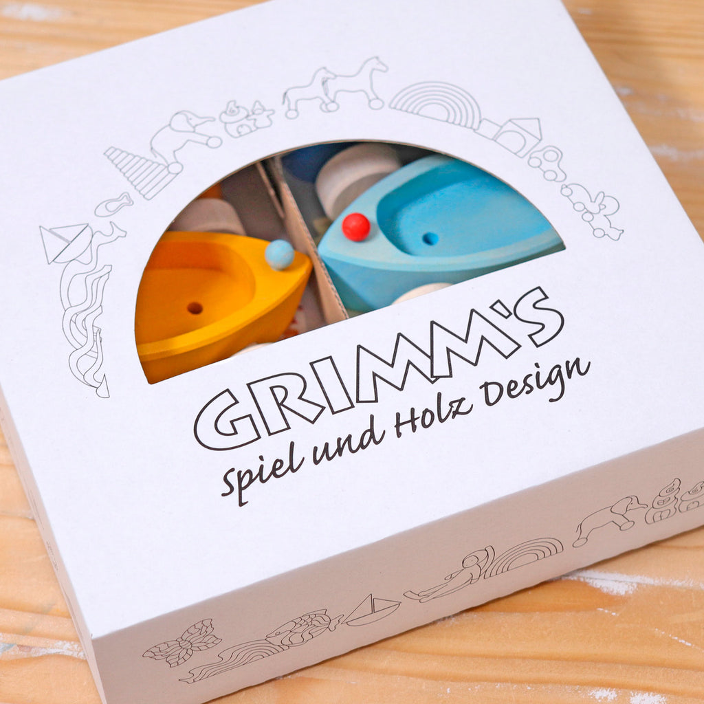 Wooden toy packaging with 'Grimm's Spiel und Holz Design' branding on a wooden surface.