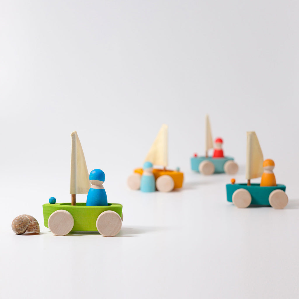 Set of colorful wooden toy sailboats on a white background