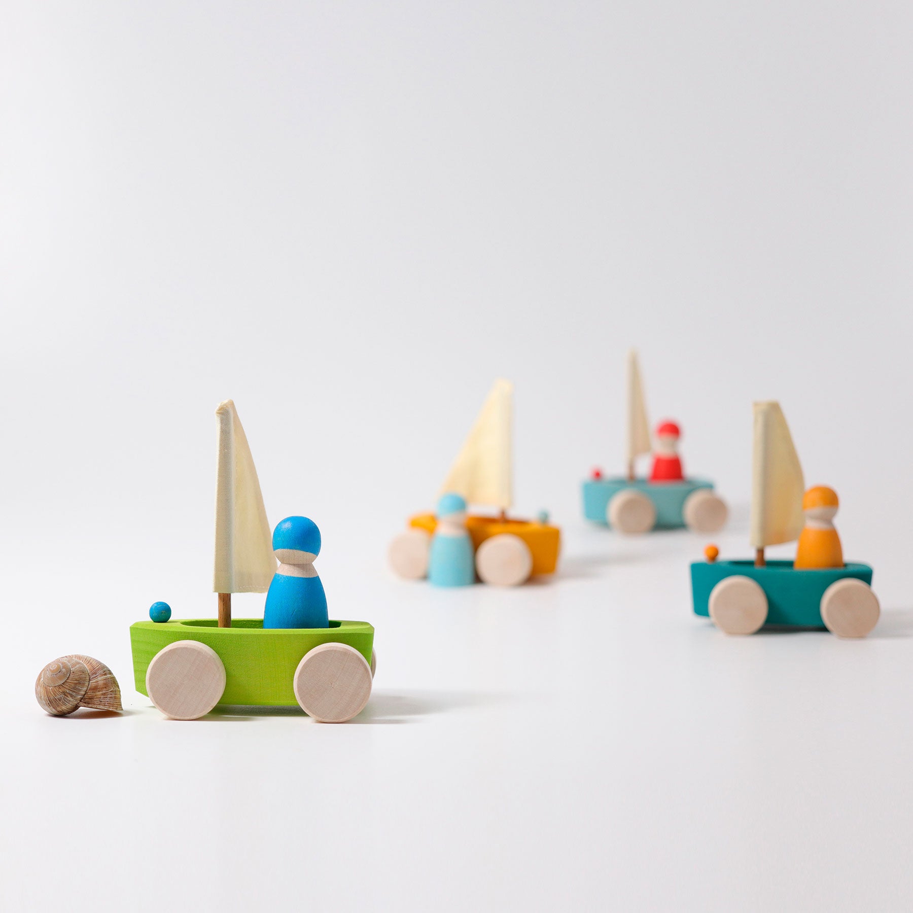 Set of colorful wooden toy sailboats on a white background