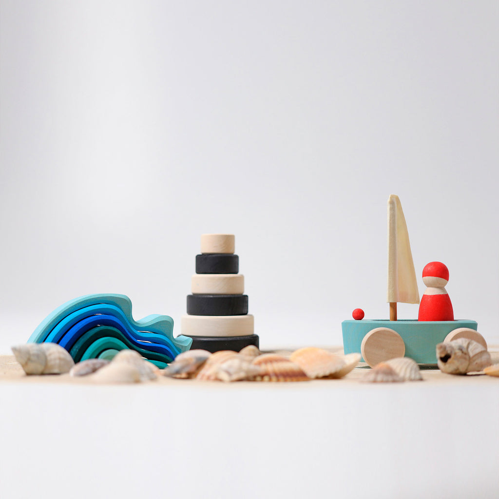 Set of wooden toys including a rainbow, stack of rings, and boat on a light background