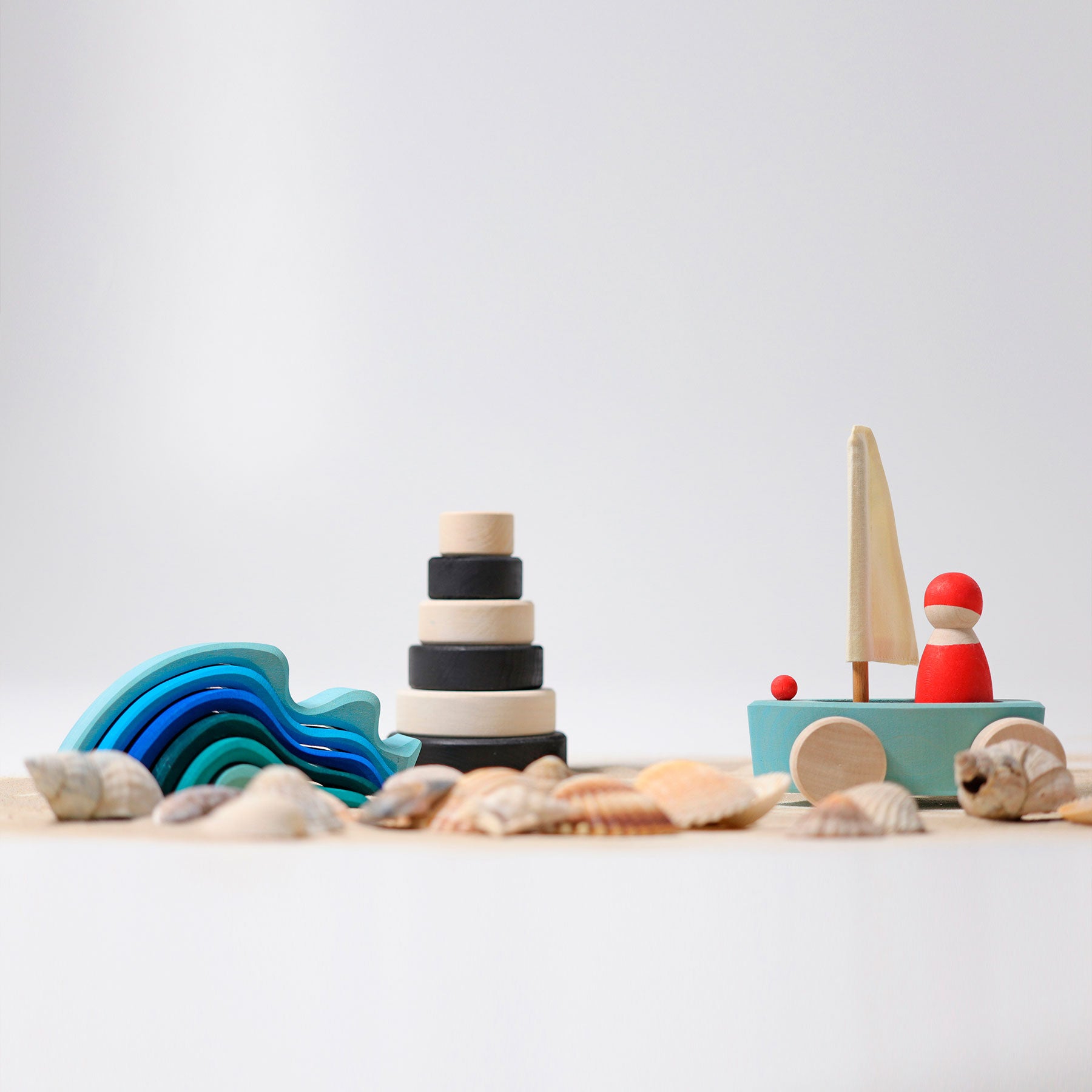 Set of wooden toys including a rainbow, stack of rings, and boat on a light background