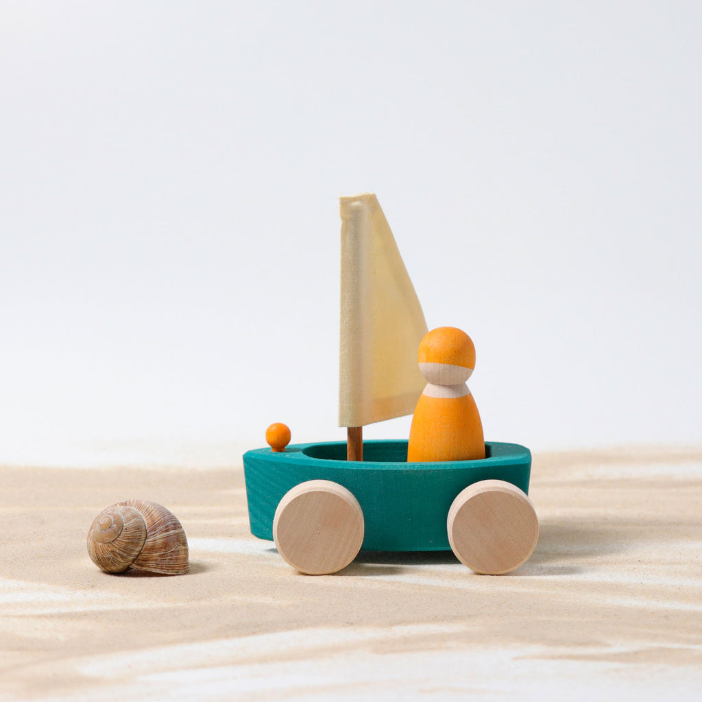 Wooden toy boat with a sail on a sandy surface