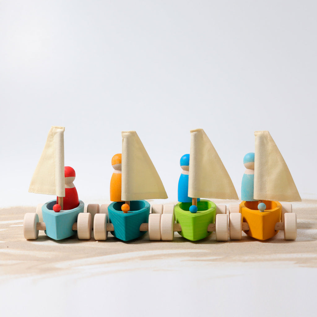 Set of colorful wooden toy sailboats on a light surface with a light gray background