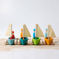 Set of colorful wooden toy sailboats on a light surface with a light gray background
