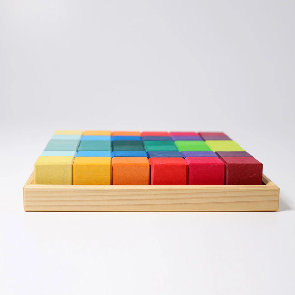 Colorful wooden blocks in a wooden tray on a light gray background